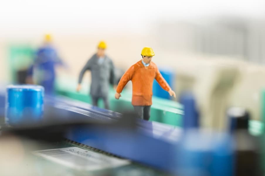 Figurines of workers in hard hats standing on industrial equipment